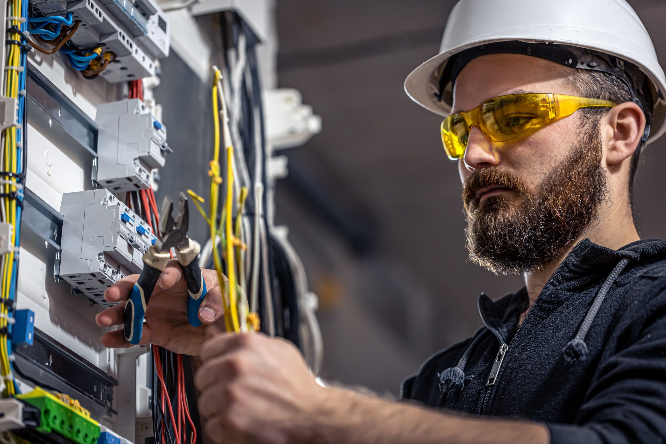 Male electrician at the checkout counter on a blurred background of a switchboard.